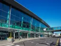 Nowoczesny budynek z przeszkloną fasadą, widoczny jest pas startowy i kładka dla pieszych. To wejście na dublin lotnisko.