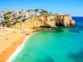 Słoneczne portugalia plaże z białymi domkami na klifie, turkusowa woda i złoty piasek.