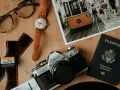 Paszport USA, aparat Canon, klisza, zegarek i okulary na drewnianym tle. Kto wydaje paszport? Rząd USA.