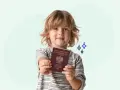 Uśmiechnięty chłopiec trzyma polski paszport. Teraz łatwo wyrobisz paszport dla dziecka online.