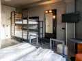 Pokój wieloosobowy w hotelu a&o Warszawa z łóżkami piętrowymi, dwoma łóżkami pojedynczymi i telewizorem.