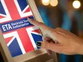 Dłoń dotyka ekranu z flagą Wielkiej Brytanii i napisem "ETA Electronic Travel Authorization". Czy do Londynu trzeba paszport? Sprawdź ETA.