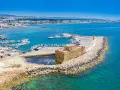 Malowniczy port na Cyprze, z zamkiem i licznymi łodziami. Widok z lotniska na turkusowe morze i wybrzeże.