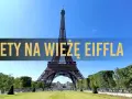 Wieża Eiffla w Paryżu, z napisem "Bilety na Wieżę Eiffla" na tle błękitnego nieba.