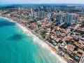 Widok z lotu ptaka na tętniące życiem brazylijskie wybrzeże z turkusową wodą, plażą pełną ludzi i nowoczesnymi wieżowcami. Czy Brazylia jest bezpieczna? To miejsce wygląda na spokojne.