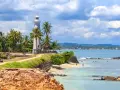 Latarnia morska na Sri Lance, otoczona palmami, z widokiem na ocean i plażę. Idealne miejsce na wakacje, warto sprawdzić wizę Sri Lanka.