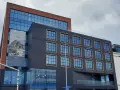Nowoczesny budynek z cegły i ciemnej fasady, z banerem zapowiadającym otwarcie Occidental Powisle Hotel, części sieci Barceló.