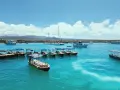 Turkusowa woda, łodzie i żaglówki czekają na Twoją galapagos wycieczka cena. Widok na wyspy i chmury.