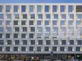 Nowoczesny hotel Puro Warszawa z licznymi oknami i pionowymi podświetlanymi elementami fasady.