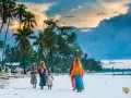 Dzieci na plaży podczas wycieczki na Zanzibar. Palmy i chmury tworzą tło dla tej sceny.