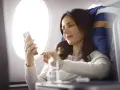 Kobieta korzysta z telefonu, ciesząc się **wifi w samolocie** podczas lotu.