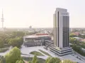Radisson Blu Hotel w Hamburgu, z wieżą telewizyjną w tle, otoczony zielenią.