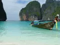 Łódź kołysze się na turkusowych wodach Maya Bay, otoczonej majestatycznymi klifami.
