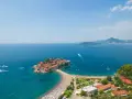Sveti Stefan, perła Czarnogóry, idealne miejsce na wycieczki. Wyspa z czerwonymi dachami, plaża, turkusowe morze i góry w tle.