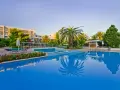 Basen hotelowy z palmami i kwitnącymi kwiatami, idealne miejsce na relaks przy Caravia Beach Kos.
