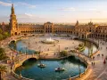 Zachód słońca nad Plaza de España w Sewilli. Ludzie pływają łódkami po kanale, podziwiając architekturę tego pięknego miasta.