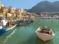 Port z łodziami rybackimi i domami na zboczu góry. Widok sugeruje, że na Sycylii jest bezpiecznie i spokojnie.