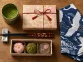 Trzy urocze japońskie słodycze wagashi, puszka matchy i ozdobne pałeczki. Idealne, by pokazać, co przywieźć z Japonii.