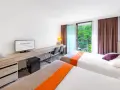 Pokój hotelowy z dwoma łóżkami, biurkiem i balkonem z widokiem na zieleń. Hotel Posejdon Gdańsk.