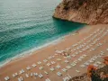 Piękna plaża w Turcji, turkusowe morze obmywa piaszczysty brzeg, a rzędy leżaków czekają na turystów.