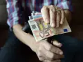 Dłoń trzyma banknoty euro, które są walutą Słowenii.