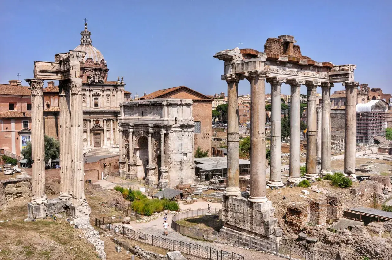 Wspaniały wyjazd do Rzymu! Ruiny Forum Romanum z łukiem i kolumnami na tle błękitnego nieba.