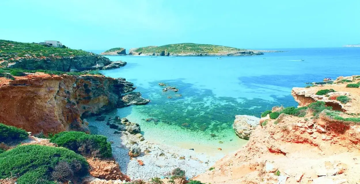 Malta last minute tanio! Widok na turkusową zatokę z klifami i zielenią. Idealne miejsce na wakacje.