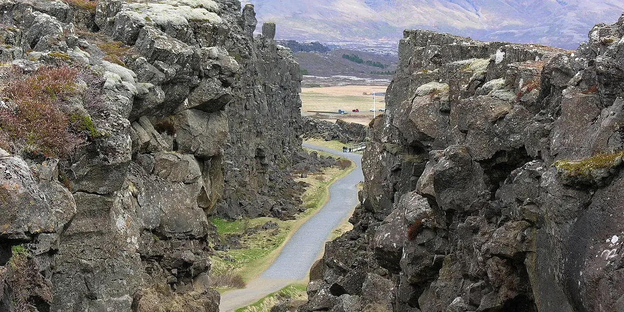 Wąwóz w Parku Narodowym Þingvellir, część Złotego Kręgu Islandii. Kamienne ściany i droga wiodąca w głąb krajobrazu.