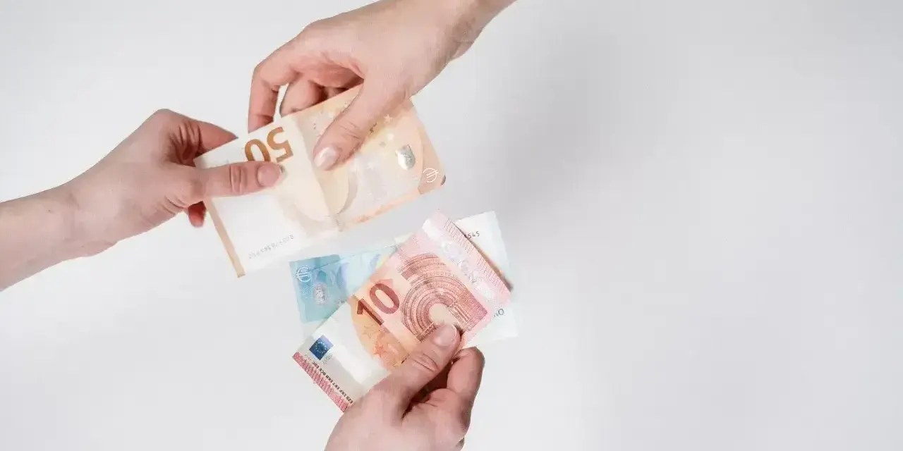 Dwie ręce przekazują sobie banknoty euro. To popularna waluta austrii, używana do codziennych transakcji.