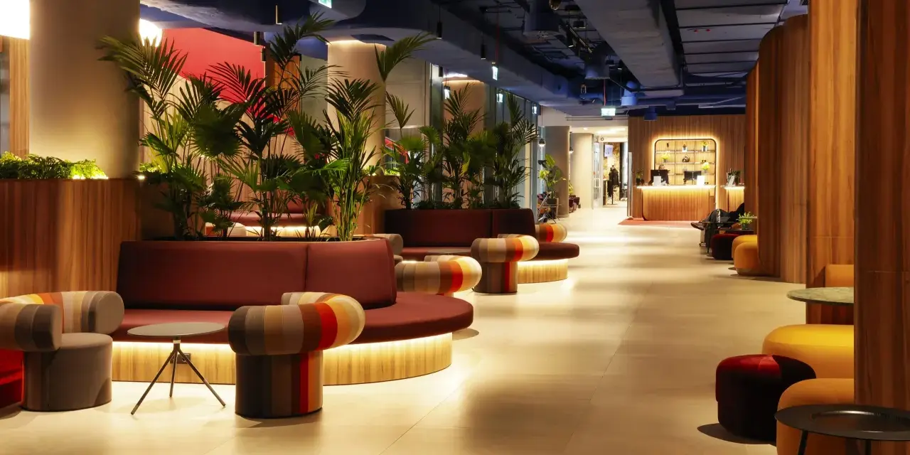 Nowoczesne wnętrze z roślinnością i kolorowymi meblami. Recepcja hotelu Mercure Warszawa Centrum wita gości.