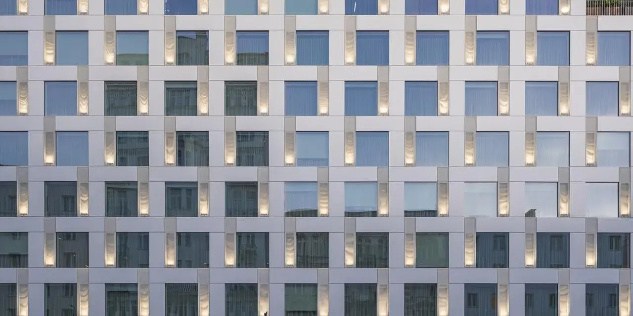 Nowoczesny hotel Puro Warszawa z licznymi oknami i pionowymi podświetlanymi elementami fasady.