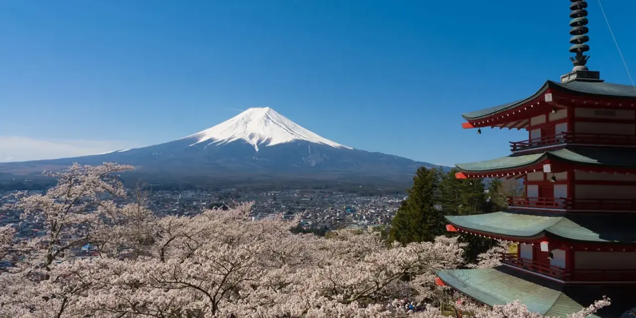 Widok na najwyższy szczyt Japonii, górę Fudżi, otoczoną kwitnącymi wiśniami i tradycyjną pagodą.