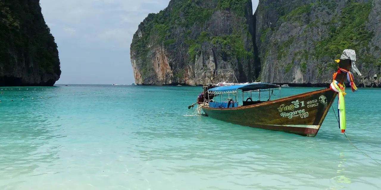 Łódź kołysze się na turkusowych wodach Maya Bay, otoczonej majestatycznymi klifami.