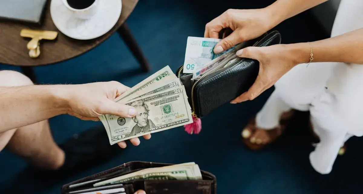 Ręce przekazują sobie pieniądze. Jedna osoba daje dolary, druga wkłada banknoty do portfela. Czy w Turcji można płacić euro?