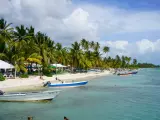 Rajski **Bavaro Beach** z palmami, białym piaskiem, turkusową wodą i łodziami.