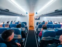 Wnętrze samolotu z pasażerami siedzącymi w rzędach. Wiele osób podróżuje, co potwierdza, że to najbezpieczniejszy środek transportu.