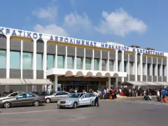 Lotnisko na Krecie, Heraklion N. Kazantzakis. Ludzie z bagażami czekają na transport przed nowoczesnym budynkiem terminalu.