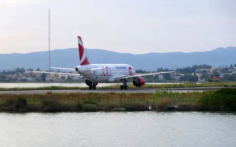 Samolot Czech Airlines na pasie startowym lotniska na Korfu, z wodą i zielenią w tle.