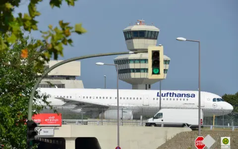 Lufthansa samolot na tle wieży kontroli lotów. To największe lotnisko w Europie, gdzie ruch jest zawsze intensywny.
