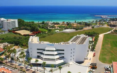 Widok z lotu ptaka na hotel Margadina Lounge Hotel z basenem i palmami, w tle błękitne morze i plaża.