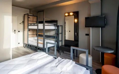 Pokój wieloosobowy w hotelu a&o Warszawa z łóżkami piętrowymi, dwoma łóżkami pojedynczymi i telewizorem.