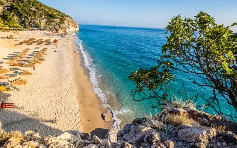 Piękna plaża w Albanii, gdzie ceny są przystępne. Słoneczny dzień, turkusowa woda i zielone wzgórza.