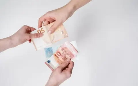 Dwie ręce przekazują sobie banknoty euro. To popularna waluta austrii, używana do codziennych transakcji.