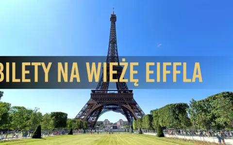 Wieża Eiffla w Paryżu, z napisem "Bilety na Wieżę Eiffla" na tle błękitnego nieba.