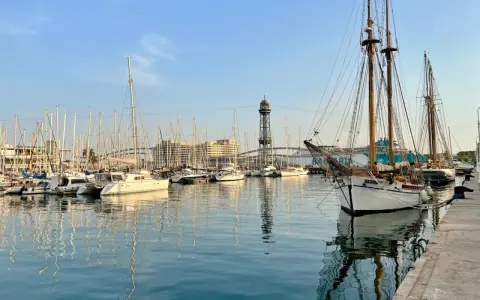 Port w Barcelonie, pełen żaglówek i statków, z wieżą widokową w tle. Czy w Barcelonie jest bezpiecznie? Tak, to spokojne miejsce.