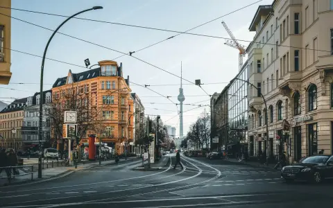 Skrzyżowanie w Berlinie z widoczną wieżą telewizyjną. Czy Berlin jest bezpieczny? Miasto tętni życiem, a ludzie swobodnie poruszają się po ulicach.