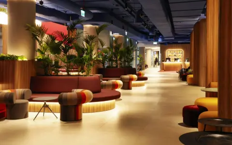 Nowoczesne wnętrze z roślinnością i kolorowymi meblami. Recepcja hotelu Mercure Warszawa Centrum wita gości.
