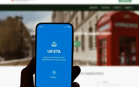 Dłoń trzyma smartfon z aplikacją UK ETA, która ułatwia uzyskanie zezwolenia na podróż do Wielkiej Brytanii.
