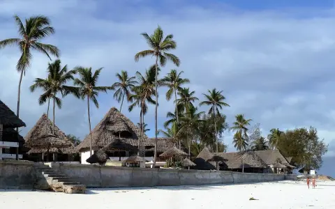 Rajskie plaże Zanzibaru, palmy i domki z krytymi strzechą dachami. Przed wyjazdem warto pomyśleć o zanzibar szczepienia.