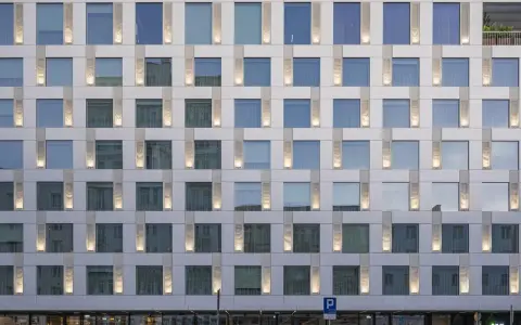 Nowoczesny hotel Puro Warszawa z licznymi oknami i pionowymi podświetlanymi elementami fasady.